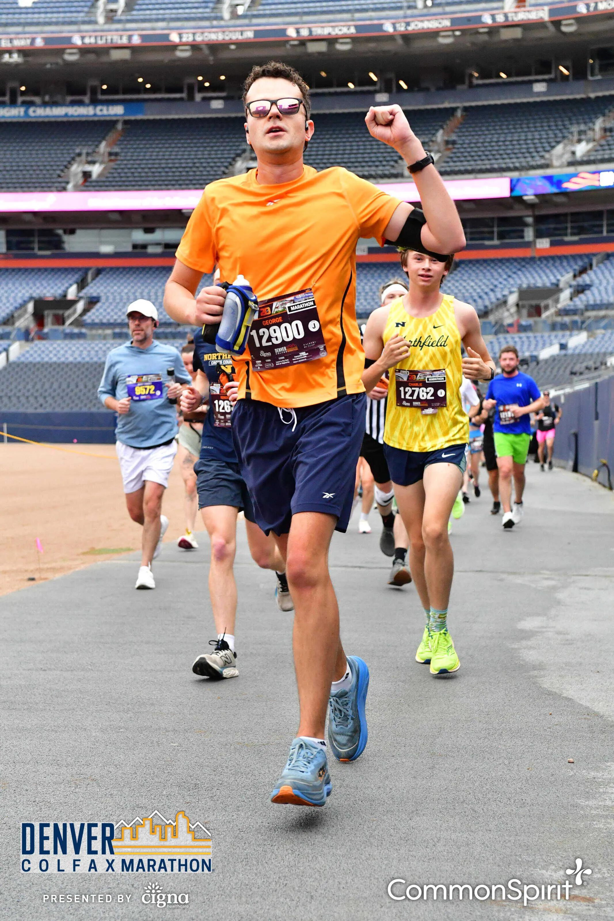 Running through the stadium on the Colfax Marathon course, bib 12900, fist raised